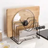A black metal pot lid and chopping board rack holder organizing cutting boards and pot lids on a clean kitchen counter.