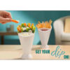 A white plastic french fries dip cone cup filled with crispy golden fries and ketchup in the attached side sauce holder.