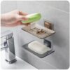 A sleek wall mounted soap drain dishes tray fixed to clean bathroom tiles holding a dry bar of soap.