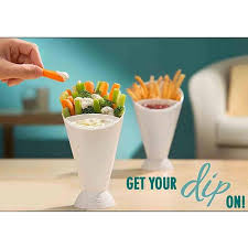 A white plastic french fries dip cone cup filled with crispy golden fries and ketchup in the attached side sauce holder.